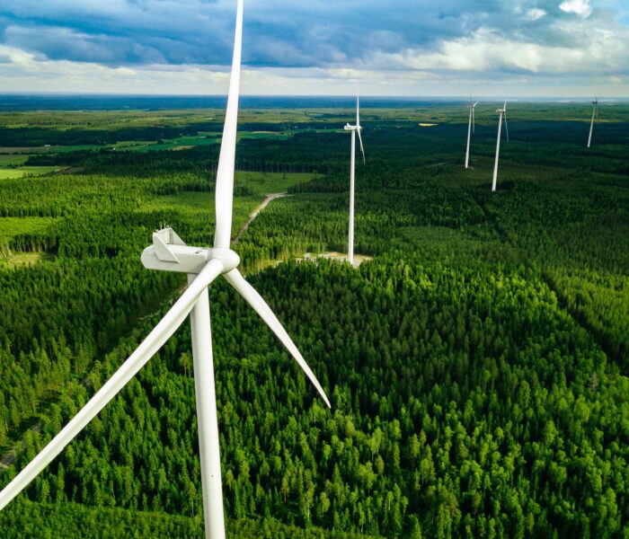 Aerial view of windmills in summer forest in Finland. Wind turbines for electric power with clean and Renewable Energy Aerial view of windmills in summer forest in Finland. Wind turbines for electric power with clean and Renewable Energy